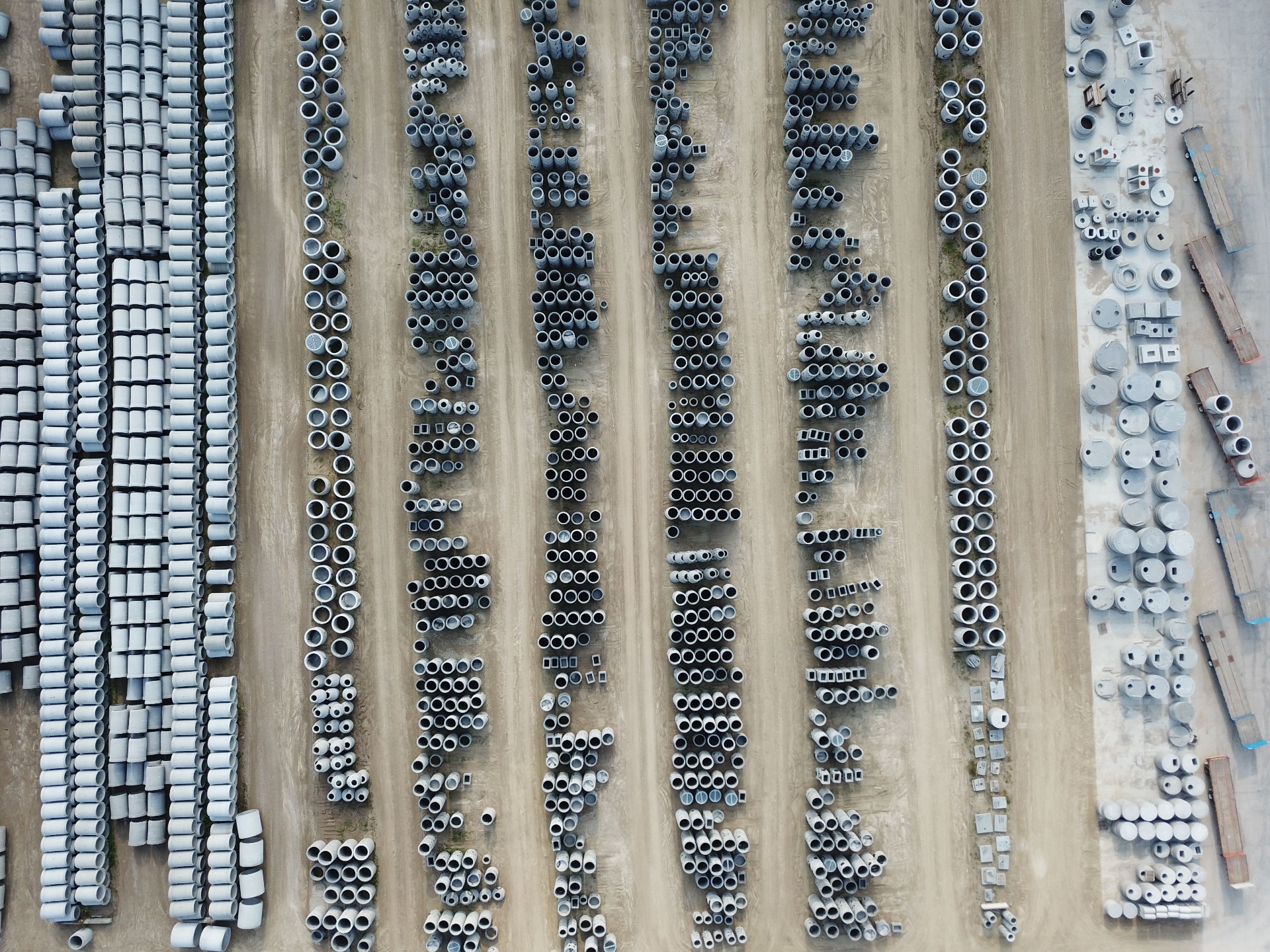 Overhead view of a pipe yard with concrete pipe stacked in neat rows on a graded lot