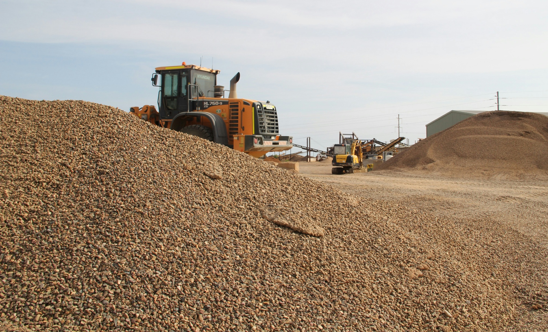 Wheel loader working large piles of gravel and stone at an industrial materials yard