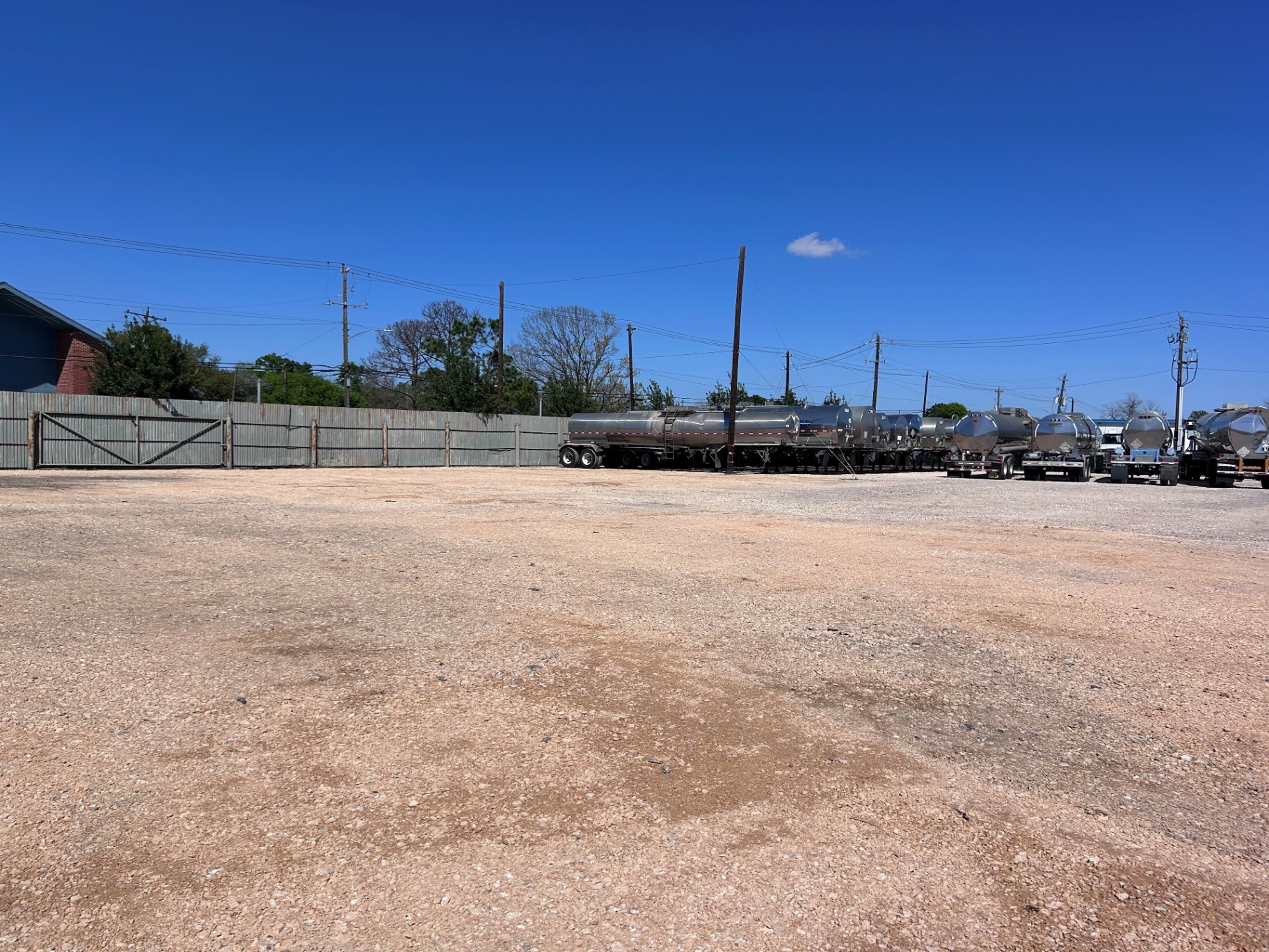 Freshly graded limestone gravel lot at a trailer maintenance shop in East Houston, with tanker trailers parked along the back fence